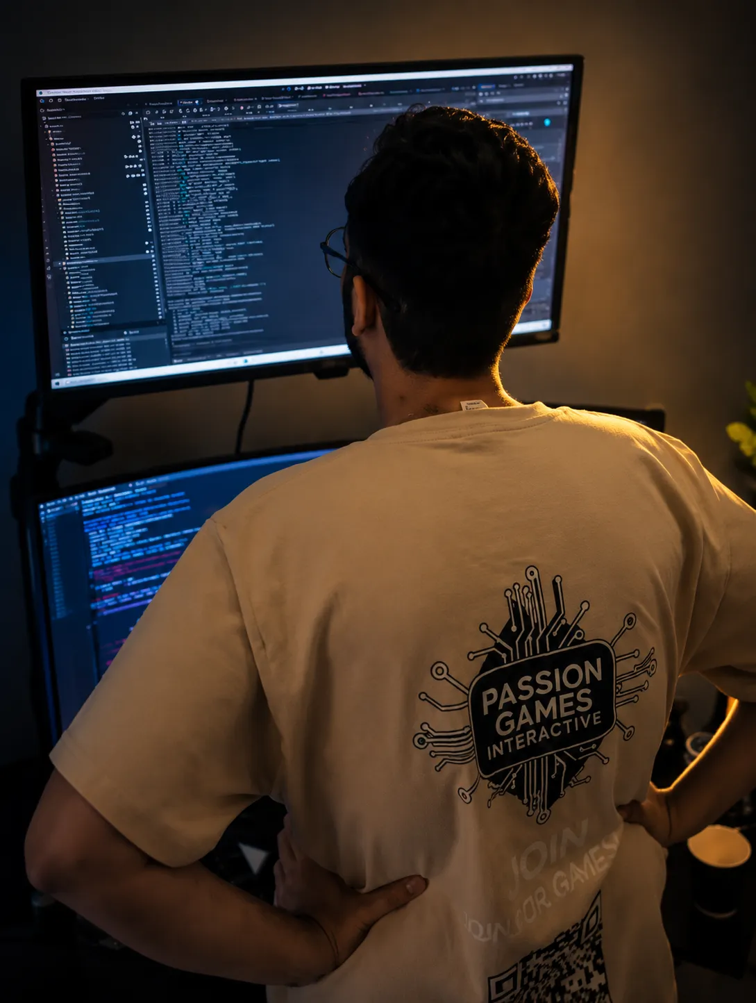 A Passion Games developer at work in front of two monitors of engine code